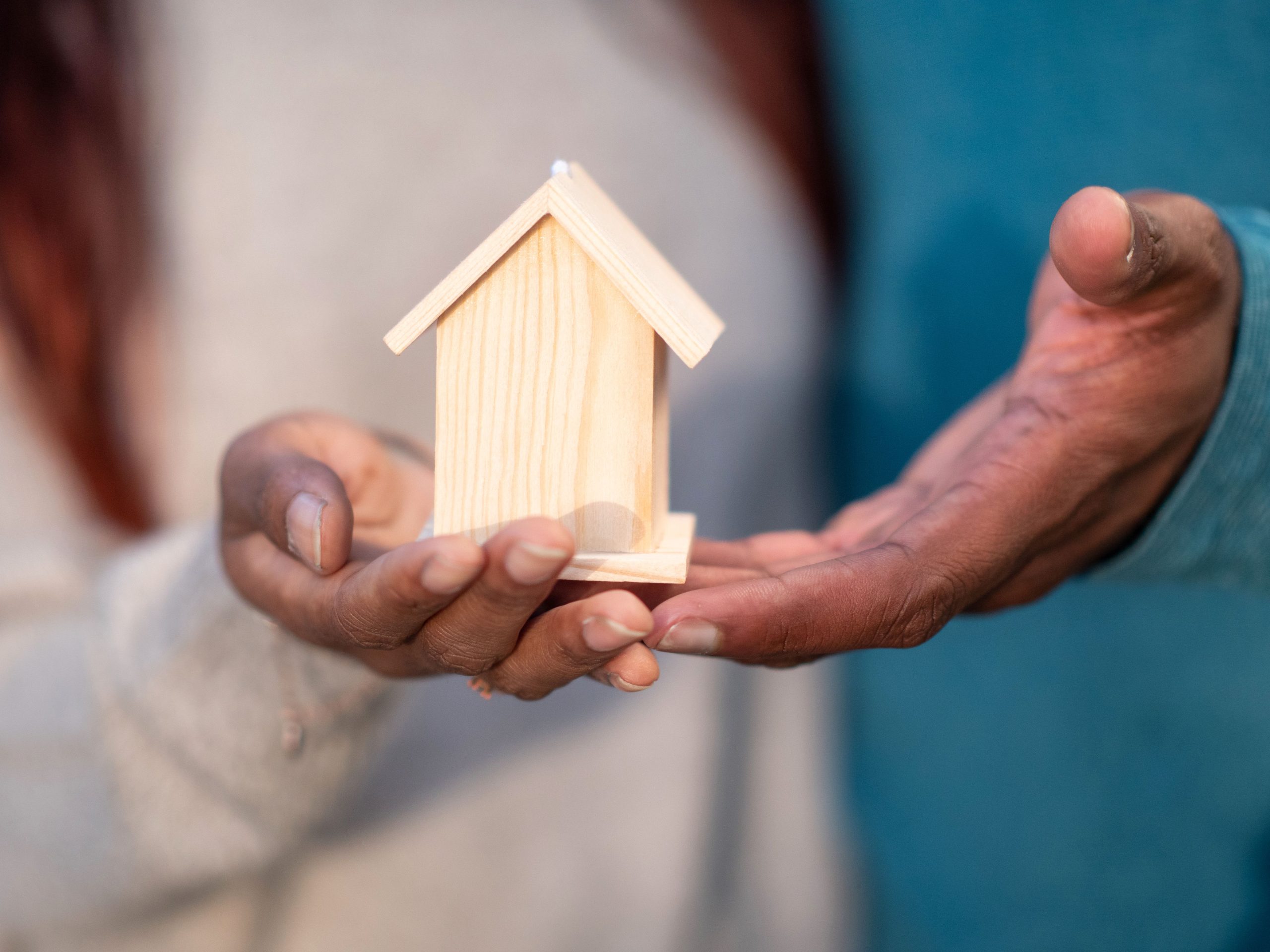 Mains tenant une maison miniature en bois
