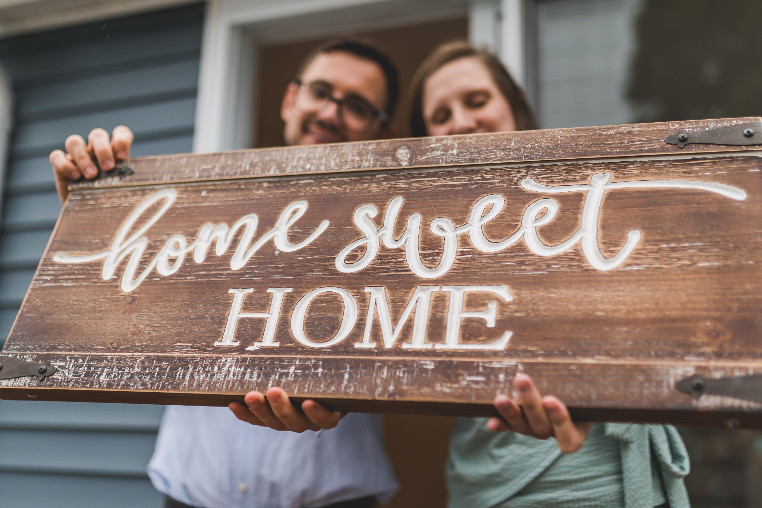 Couple souriant avec une pancarte home sweet home