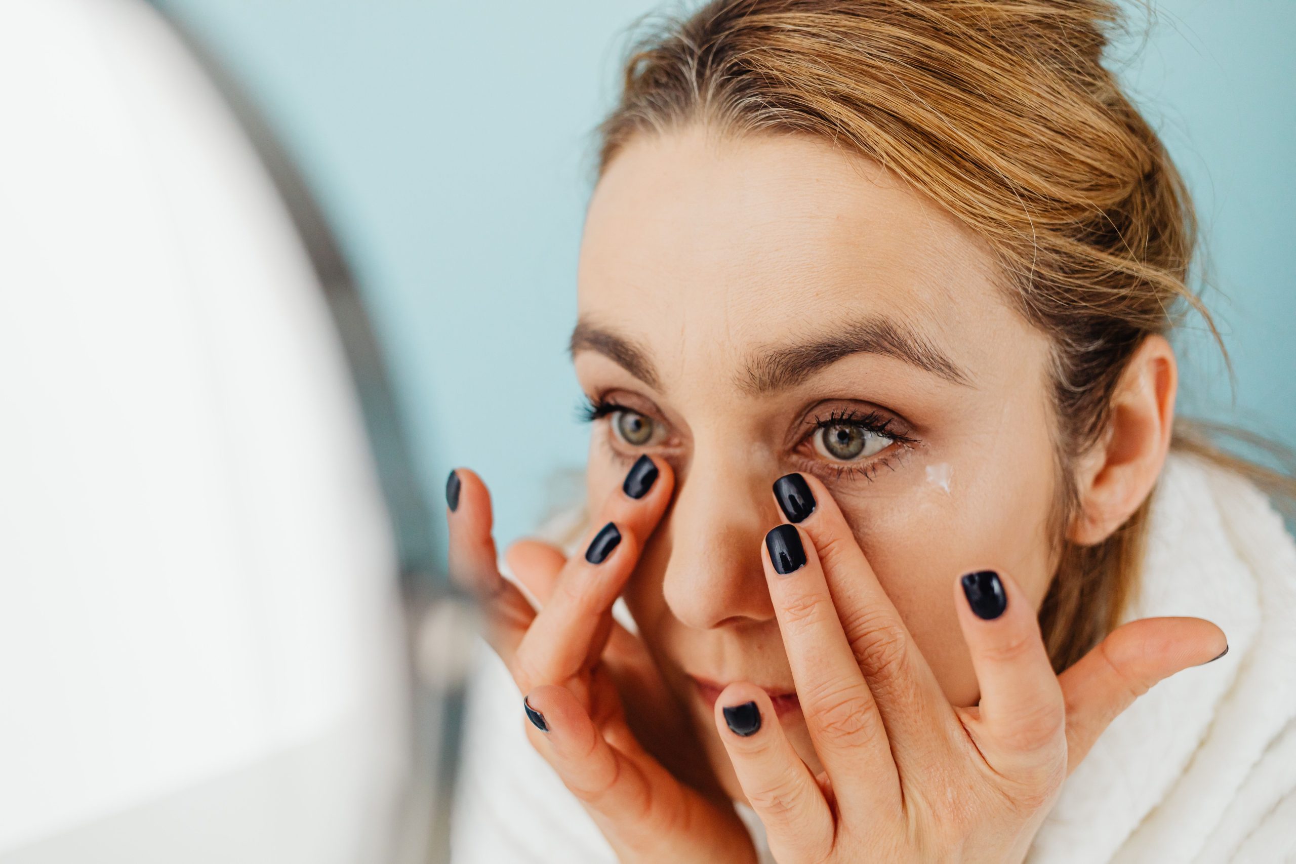 Femme appliquant une crème devant un miroir
