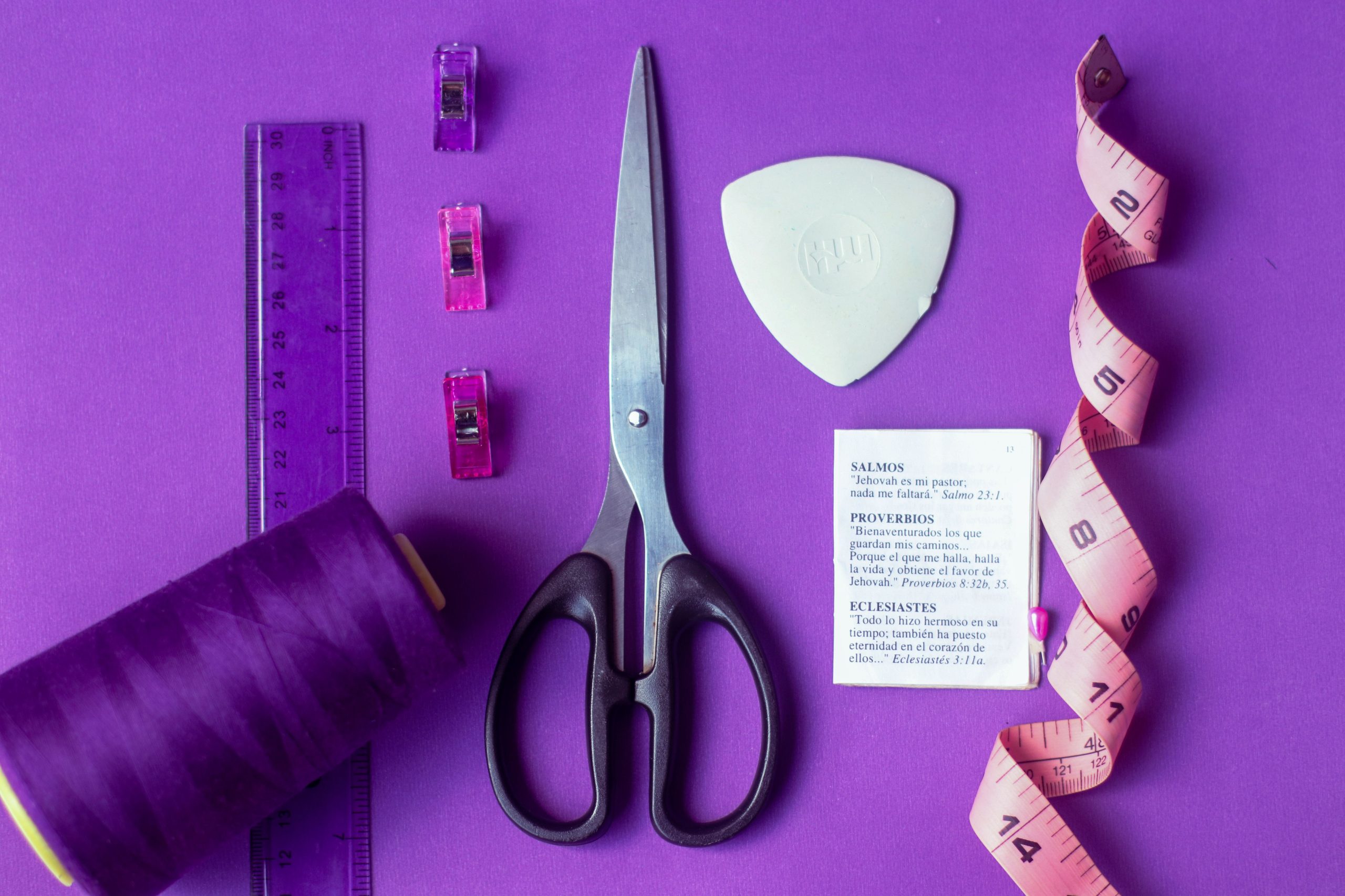Ciseaux, mètre ruban et fil sur fond violet