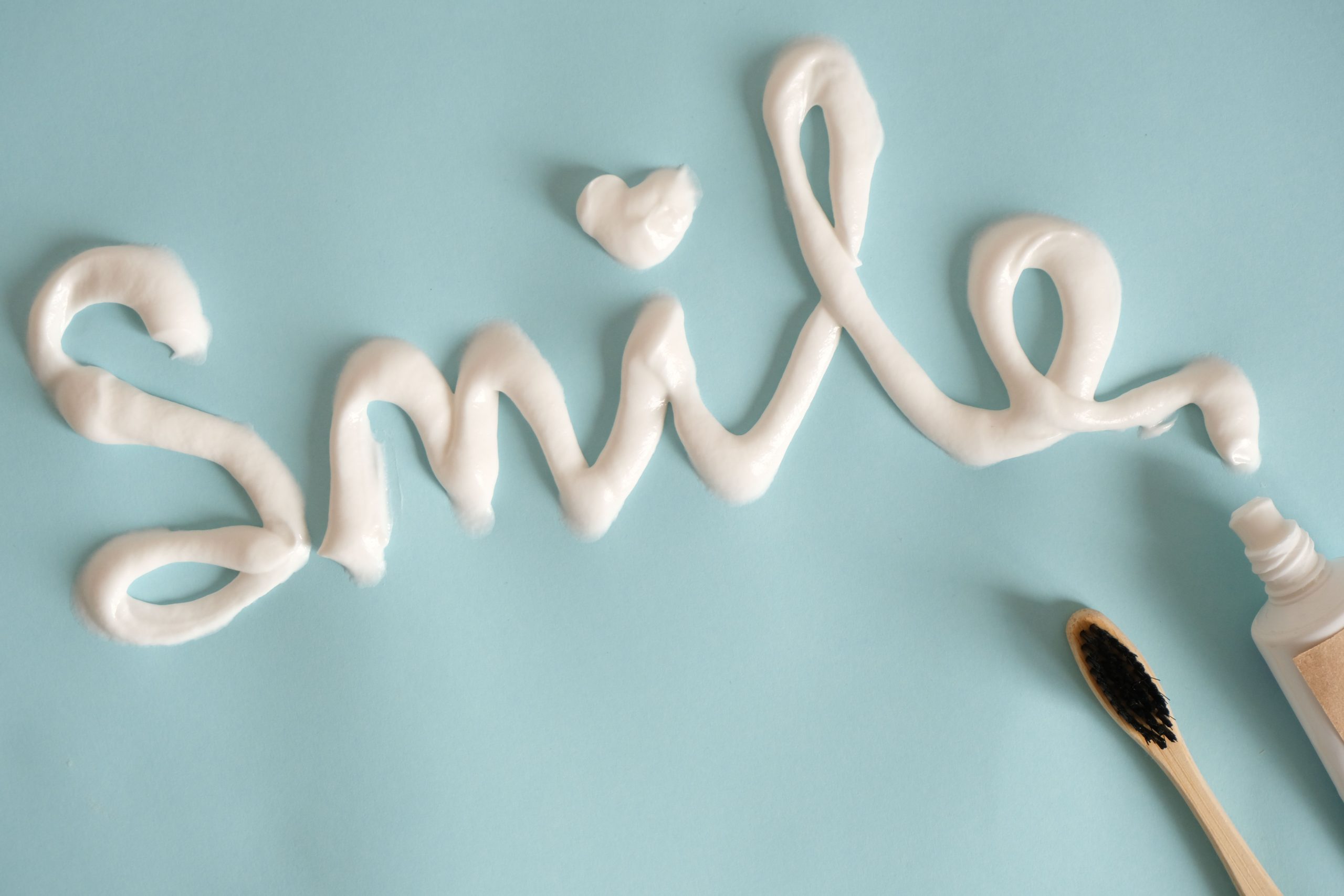 Dentifrice formant le mot Smile sur fond turquoise